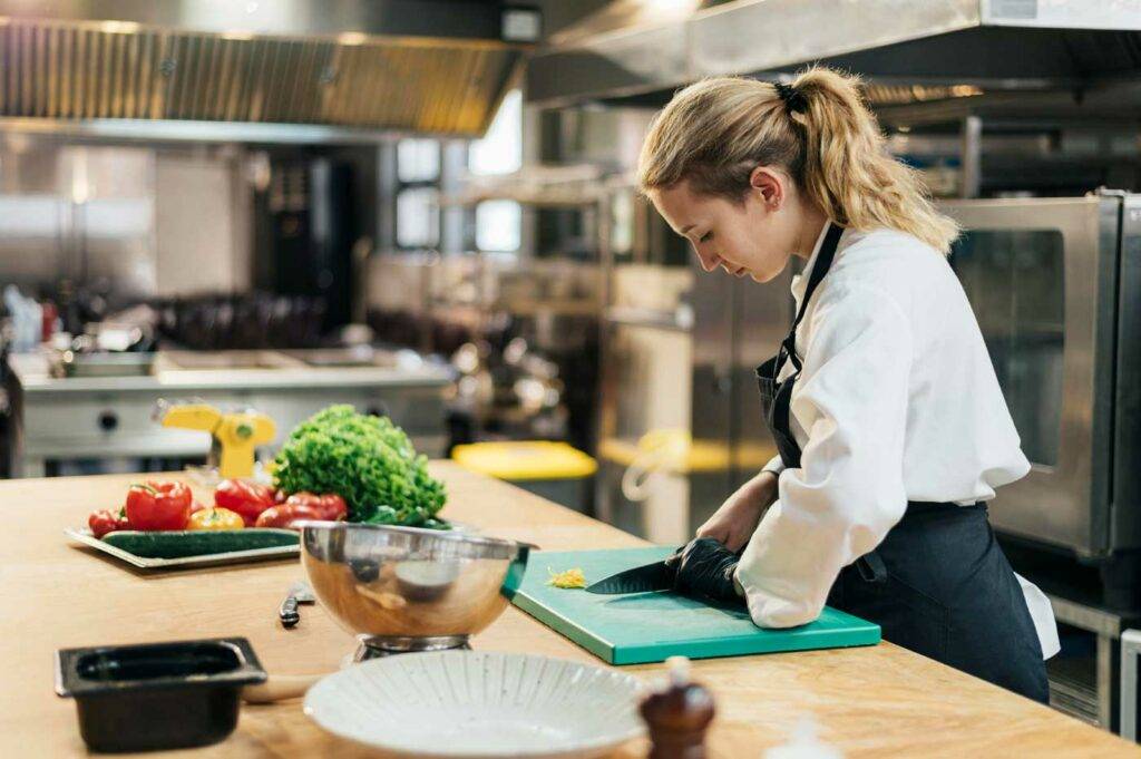 Köchin schneidet Gemüse in einer professionellen Küche – Küchenjob und Gastronomie in Dresden