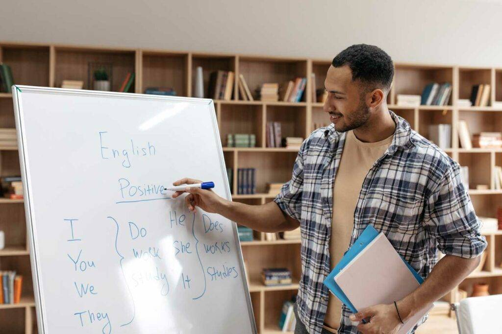 Englischlehrer erklärt englische Grammatik am Whiteboard in der Bibliothek – Lehramt Stellenangebote in Dresden
