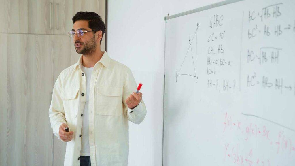 Mathematiklehrer im Klassenzimmer erklärt Geometrie an der Tafel mit rotem Stift – Lehrer Stellenangebot in Dresden