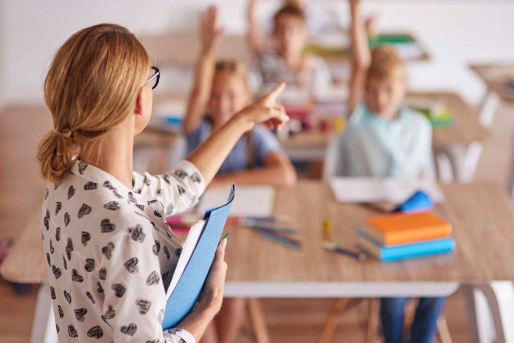 Lehrerin zeigt nach vorn im Unterricht, während Schülerinnen und Schüler sich melden – Stellenangebote an Schulen in Dresden