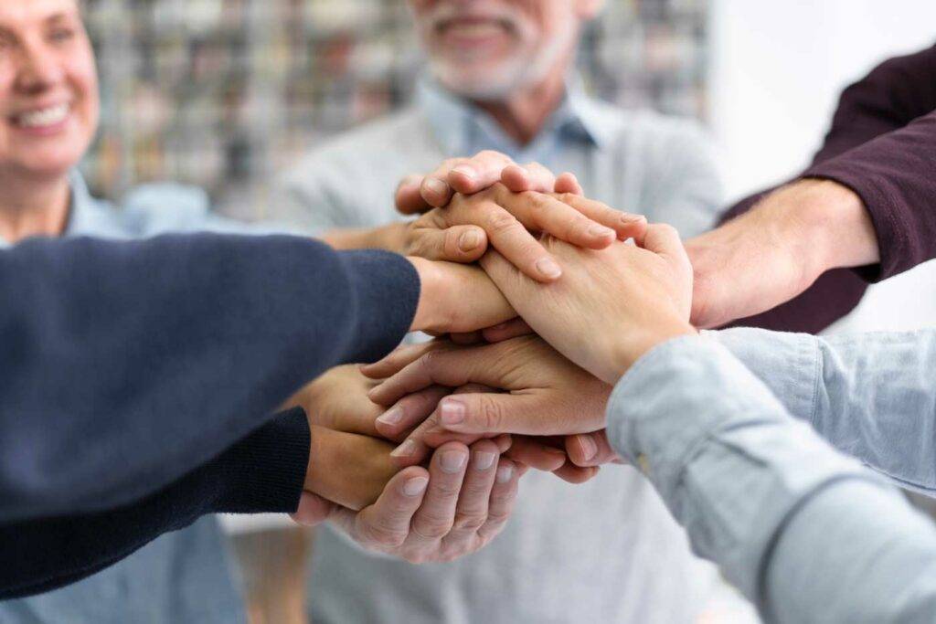 Team legt die Hände zusammen und zeigt Teamgeist – Zusammenarbeit und Jobs in Dresden