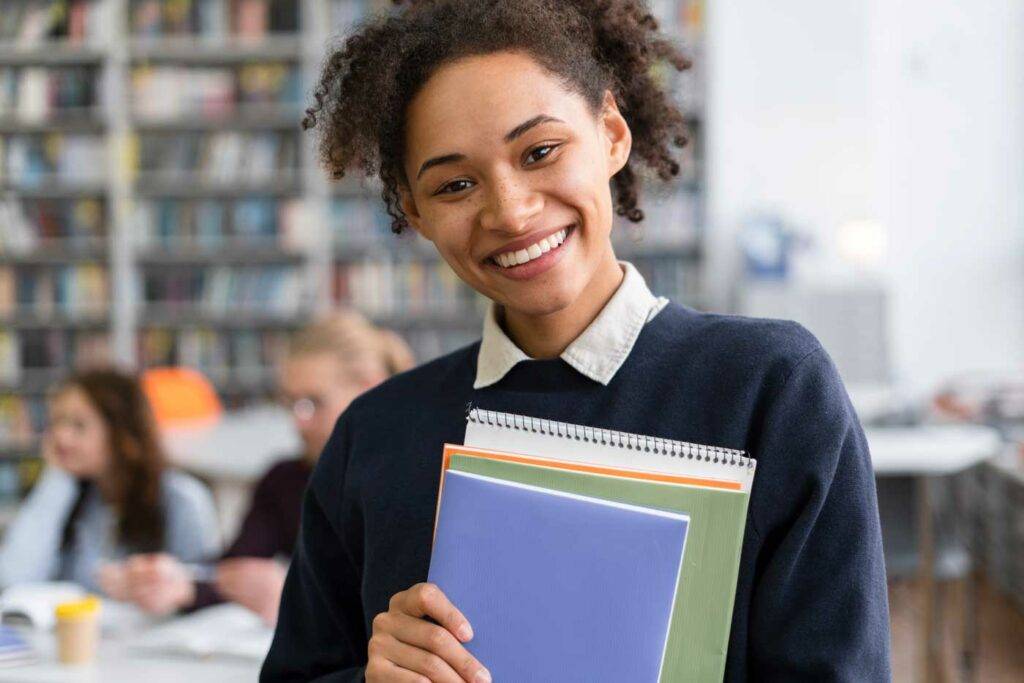 Lächelnde Lehrerin mit Ordnern im Klassenzimmer – Stellenangebote für Lehrkräfte in Dresden