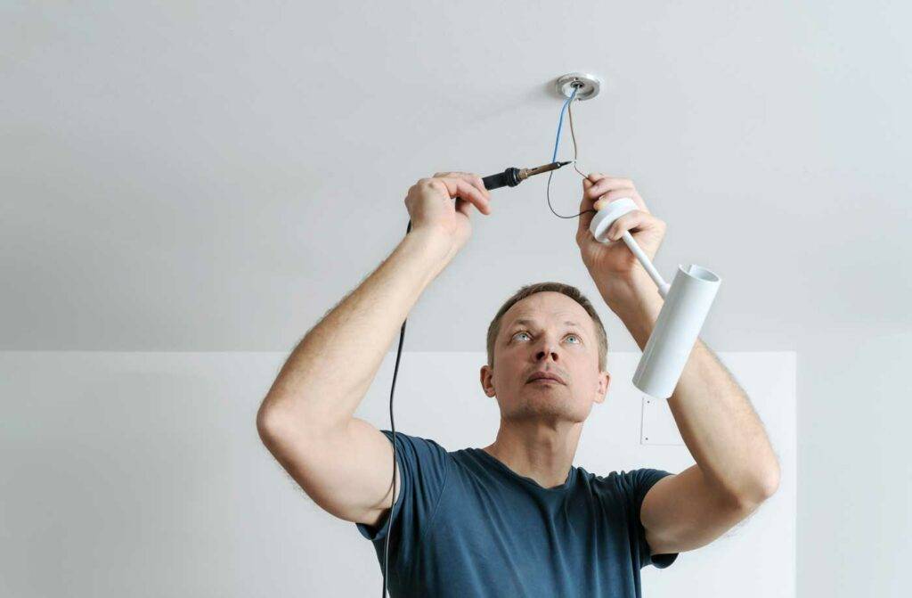 Techniker oder Hausmeister schließt eine Deckenlampe an in der HOGA Schule Dresden
