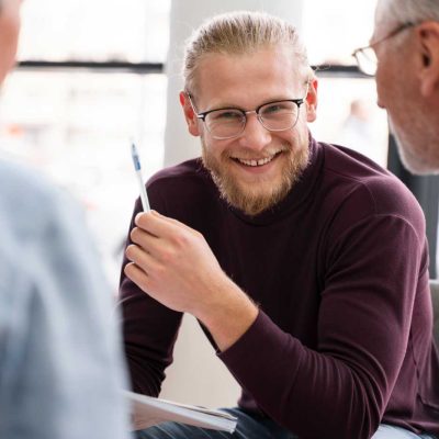 Lehrer Dozent Meeting Dresden Männlicher Lehrer oder Dozent lächelt in einer Besprechung und tauscht sich mit Kolleginnen aus – Bildung und Jobs in Dresden